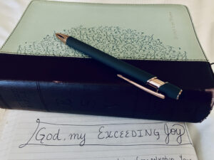 Bible and notebook with words reading "God is my exceeding joy"